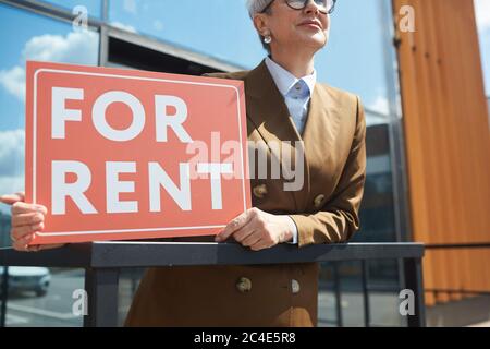 Primo piano di agente immobiliare con cartello per Noleggio in piedi all'aperto Foto Stock
