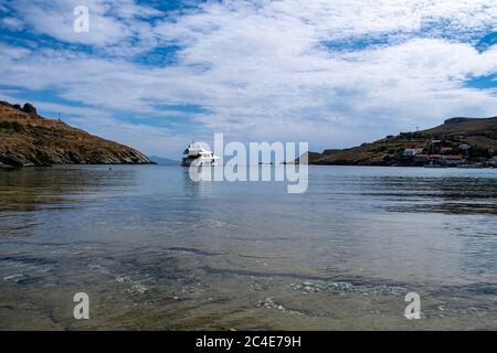 Kea, Otzias, Grecia. Yacht di lusso bianco è ancorato di fronte alla terra dell'isola di Tzia, nel mezzo del mare blu trasparente e calmo. Cielo nuvoloso Foto Stock