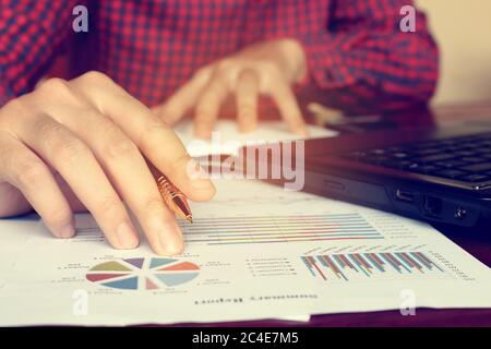 Analisi di dati con imprenditore tenendo pen a grafici e grafico per scoprire il risultato. Foto Stock