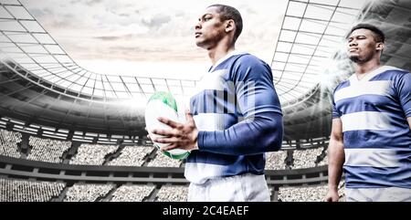 Immagine digitale composita di due giocatori di rugby che tengono la palla nello stadio sportivo Foto Stock