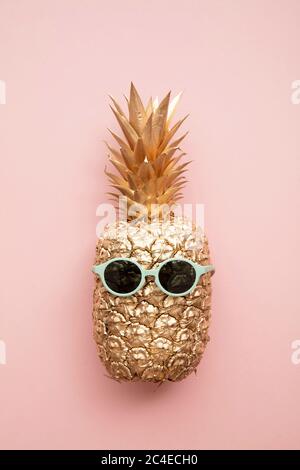 Oro ananas trendy con occhiali da sole estivi su rosa Foto Stock