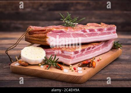 Pancetta affumicata fatta in casa su tavola di legno Foto Stock