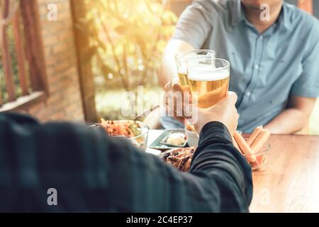 Primo piano di un uomo adulto a mano che tiene un bicchiere di birra e che si aggraffa insieme. Foto Stock