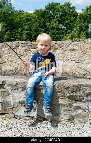 Ragazzo di tre anni seduto su un muro accanto al sontuoso castello di Kamieniec Ząbkowicki, nella contea di Ząbkowice Śląskie, basso Voivodato della Slesia, Polonia Foto Stock