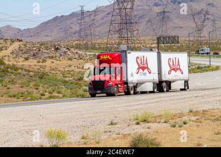 Apple Valley, CA / USA – 16 maggio 2020: Un semirimorchio di Sala Freight rosso e bianco su una rampa dell'Interstate 15 nel deserto di Mojave vicino alla città di App Foto Stock