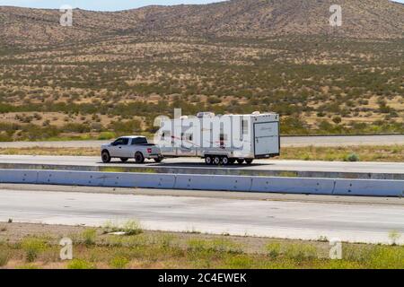 Apple Valley, CA / USA – 16 maggio 2020: Un camion che traina un rimorchio RV sull'Interstate 15 nel deserto di Mojave vicino alla città di Apple Valley, California. Foto Stock