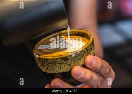 Primo piano di un maschio che fa un latte art Foto Stock