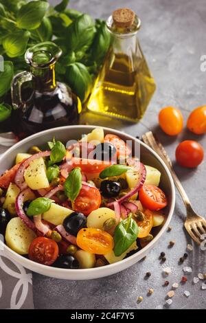 Insalata di patate con pomodori, olive, capperi, cipolla rossa, cucina italiana. Insalata Pantesca. Foto Stock