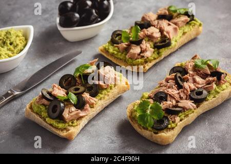 Bruschetta con tonno, olive e avocata spalmata. Foto Stock