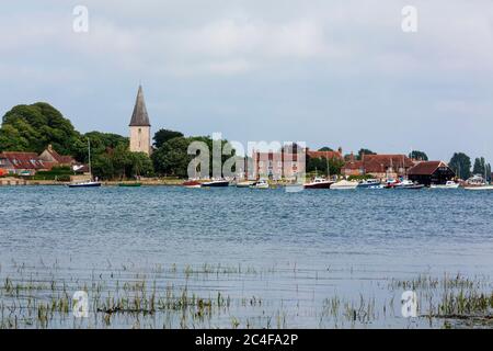 Alta marea Bosham nel Sussex occidentale attraverso il porto di Chichester in un giorno estivo. Villeggianti e picnic sul prato di fronte alla Santissima Trinità. Foto Stock