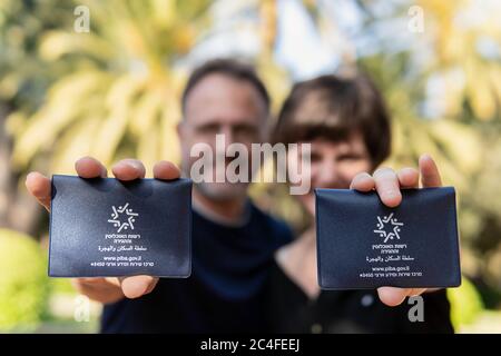 Haifa, Israele, 28 novembre 2019. Felice coppia di nuovi rimpatri israeliani mostra nuovi passaporti provvisori israeliani rilasciati di recente in piedi in un bellissimo giardino Foto Stock