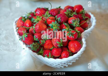 Fragole dolci nel cestino. Simbolo dell'amore. Ciotola a forma di cuore, fragole succose estive . Cuore bianco di fragola in un cesto . Foto Stock