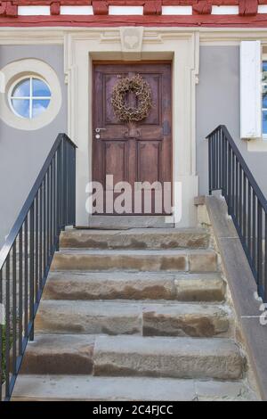 Porta di fronte in legno con scalini in pietra in villaggio rurale Foto Stock