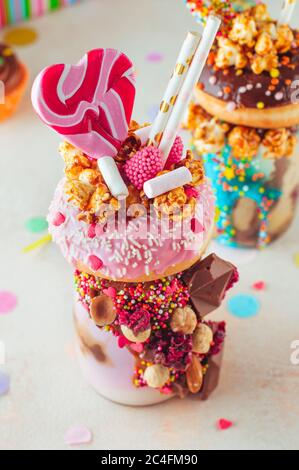 Raspberry frak agita con ciambella, popcorn caramello e dolci su sfondo festa. Messa a fuoco selettiva. Foto Stock