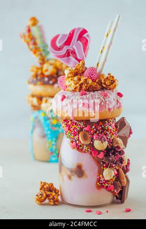 San Valentino frullato lampone frullato con ciambella, popcorn caramello e dolci su sfondo beige. Messa a fuoco selettiva. Foto Stock