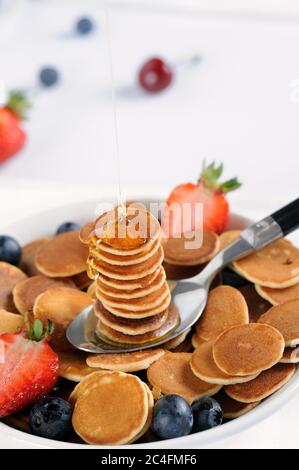 Gustosa colazione con mini pancake di cereali con fragole e mirtilli. Mini pancake di cereali è nuovo cibo alla moda per le attività. Foto Stock