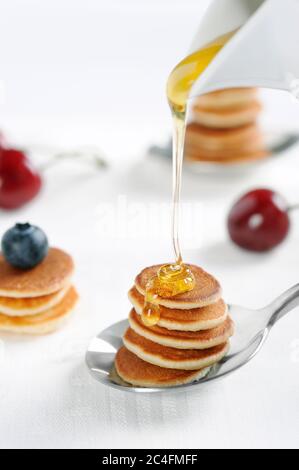 Gustosa colazione con mini pancake cereali con fragole e mirtilli. Mini pancake cereali è nuovo cibo alla moda per attività. Orientamento verticale. Foto Stock