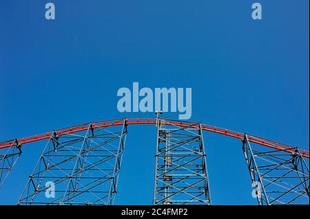 La struttura dipinta di rosso e blu delle montagne russe Big One contro il cielo in estate Foto Stock