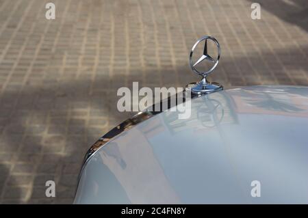 Primo piano di un logo Mercedes su una delle loro auto, a sinistra è uno sfondo neutro che può servire da spazio di copia Foto Stock