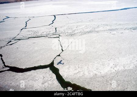 Vista aerea della superficie ghiacciata del lago Kluane e di un'ombra di aeroplano, nelle montagne di St. Elias, nel Parco Nazionale di Kluane, territorio di Yukon, Canada. Foto Stock