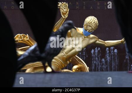 New York City, Stati Uniti. 26 Giugno 2020. Prometheus, una scultura in bronzo dorato del 1934 di Paul Manship situata in Rockefeller Plaza, è adornata con una maschera blu per promuovere la seconda fase della riapertura di New York City e incoraggiare l'allontanamento sociale per fermare la diffusione del COVID-19, New York, NY, 26 giugno 2020. (Anthony Behar/Sipa USA) Credit: Sipa USA/Alamy Live News Foto Stock