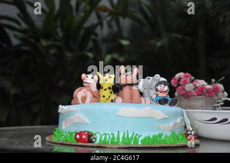 Torta di compleanno per bambini con figure animali e glassa paesaggistica Foto Stock