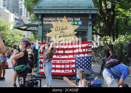 25 giugno 2020, New York, New York, USA: Dopo settimane di proteste contro la brutalità della polizia e l'ingiustizia razziale, i dimostranti di New York si accamparono di fronte al municipio per chiedere un miliardo di dollari di tagli ai finanziamenti della NYPD prima della scadenza del budget della città del 1° luglio. Il campo che si chiama 'Occupy City Hall' appese un cartello e una bandiera americana che mostra 'Black Lives Matter' all'ingresso della stazione ferroviaria. Secondo i sostenitori della riforma della polizia, il budget della polizia di circa 6 miliardi di dollari deve essere ridotto in modo significativo e reinvestito in alloggi, assistenza sanitaria e altri servizi sociali. (Immagine di credito: © Foto Stock