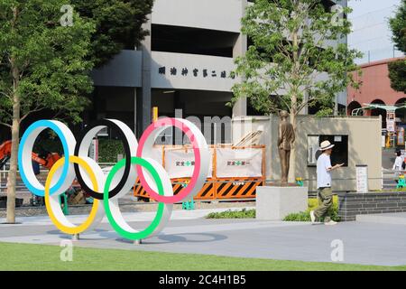 Un monumento agli anelli Olimpici situato fuori dal Museo Olimpico del Giappone. Una statua del fondatore delle Olimpiadi Pierre de Coubert e lavori stradali sono sullo sfondo. Foto Stock