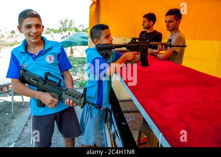 I ragazzi turchi sparano armi giocattolo in una tenda da galleria di tiro allestita a Edirne in Turchia durante il Kirkpinar Turkish Oil Wrestling Festival. Foto Stock