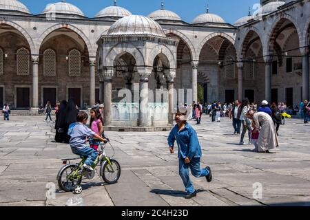 I bambini giocano nel magnifico cortile della Moschea Blu nel quartiere Sultanahmet di Istanbul, in Turchia. La moschea fu costruita nel 1606. Foto Stock