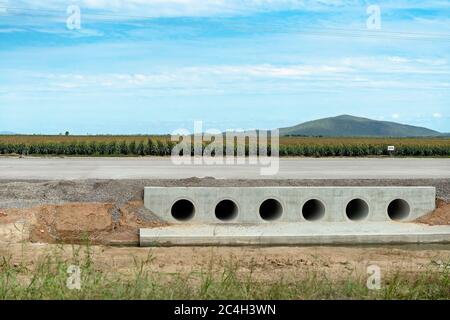 Drenaggio di fognature in lavori stradali su un'autostrada rurale con un raccolto di grano in background Foto Stock