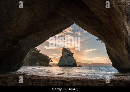 Tramonto, Cove della cattedrale, Penisola di Coromandel, Nuova Zelanda. Vista attraverso il rock arco verso Te Hoho Rock Foto Stock