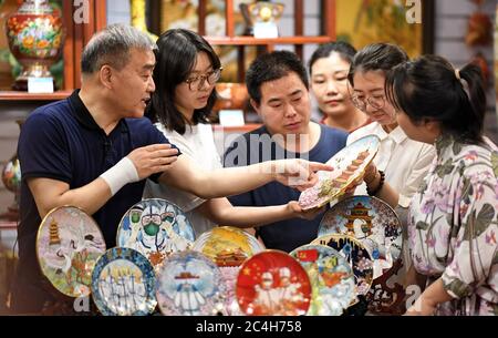 (200627) -- PECHINO, 27 giugno 2020 (Xinhua) -- Foto scattata il 10 giugno 2019 mostra l'artista Zhong Liansheng(L) e altri artigiani che controllano un'illustrazione di cloisonne di nuovo disegno a Pechino, capitale della Cina. In Cina, 'Jingtaan' rappresenta una cloisonne speciale lavorata in rame e porcellana. Introdotto dai paesi arabi durante la dinastia Yuan (1271-1368) e divenuto popolare durante gli anni 'Jingtai' della dinastia Ming (1368-1644), la cloisonne Jingtauan usa rame rosso come corpo, con disegni strutturati con fili di rame e verniciati con smalto. La realizzazione deve passare attraverso Foto Stock