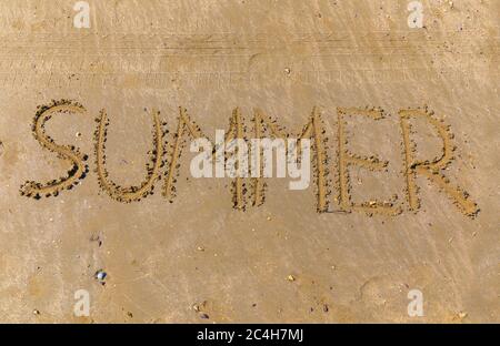 La parola estate scritta da un bastone sulla sabbia di una spiaggia Foto Stock