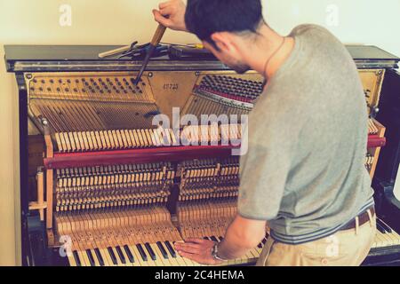 Processo di sintonizzazione del pianoforte. Primo piano della mano e strumenti di sintonizzazione che lavorano al pianoforte a coda. Vista dettagliata di piano verticale durante una sintonizzazione Foto Stock