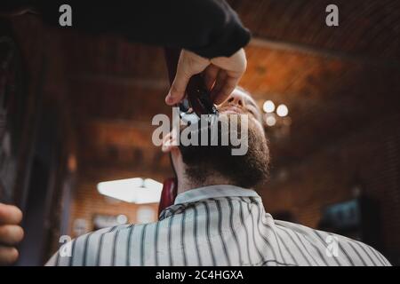 Barber taglia la barba a un ragazzo brutale Foto Stock