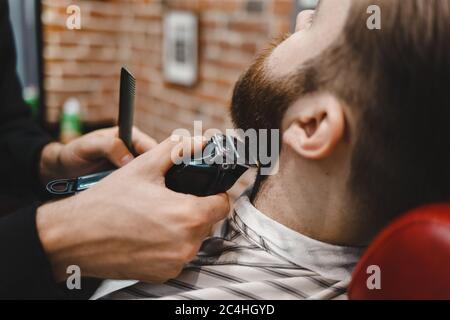 Processo di taglio della barba per barbiere. Uomo brutale che si prende cura della barba Foto Stock