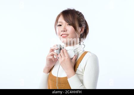Carina ragazza asiatica che indossa una cuffia sul collo e sorridente. Foto Stock