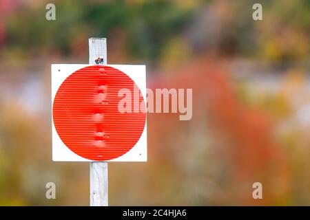 Un grande puntino rosso luminoso su un cartello attaccato ad un bastone. Il punto indica che la caccia e l'intrappolamento non sono consentiti. Foto Stock