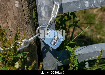 lucchetto combinato in acciaio su un lato esterno del cancello Foto Stock
