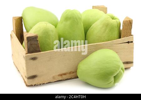 Chayote Fruit (Sechium edulis) e un taglio in una cassa di legno su sfondo bianco Foto Stock