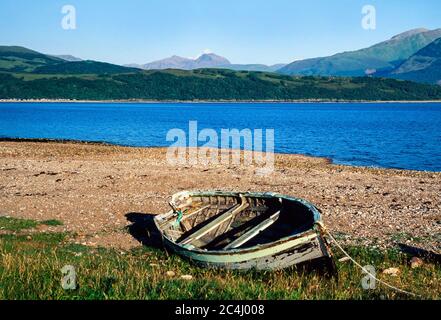 Barca a remi abbandonata su una spiaggia di ciottoli, Scozia. REGNO UNITO. Vista sulla montagna ben Nevis sullo sfondo Foto Stock