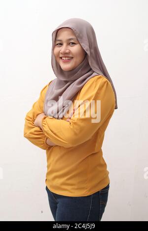 Ritratto di donna musulmana asiatica che indossa hijab sorridente amichevole con le braccia incrociate, gesto fiducioso, donna d'affari di successo, vista laterale isolato su wh Foto Stock