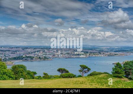 Una vista distante dall'alto sulla tenuta del Monte Edgecumbe che guarda attraverso l'estuario del Tamar verso Plymouth City con Dartmoor Nat. Parcheggiare nella parte posteriore. Foto Stock