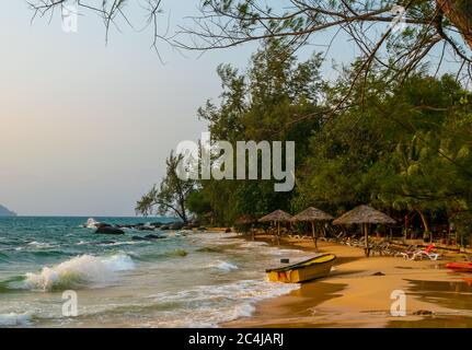 Una bellissima spiaggia con ombrelloni, sedie a sdraio e barche a Long Set Beach, Koh Rong, Cambogia Foto Stock