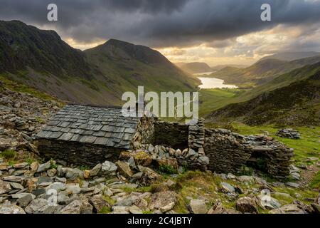 Warnscale Mountain Bothy con le nuvole scure Moody e Buttermere Lake in lontananza. Lake District, Regno Unito. Foto Stock