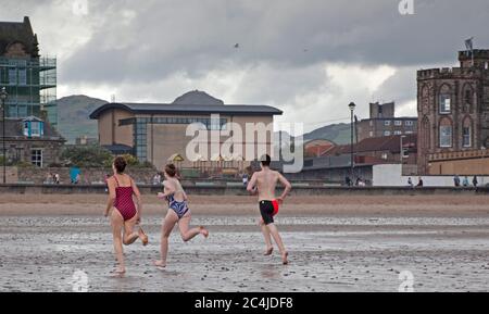 Portobello, Edimburgo, Scozia, Regno Unito. 27 giugno 2020. Non molto affollato al mare e lungomare il sabato pomeriggio, il tempo nuvoloso con una tempesta e pioggia pesante prima di ripulire per un po', Non ha interrotto una famiglia che si è scesi per un tuffo e la polizia auto con due ufficiali che non hanno avuto alcun motivo per bagnarsi. Foto Stock