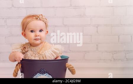 Carino neonato in borsa a secchio decorazione creativa. Bambina seduta all'interno del recipiente Foto Stock