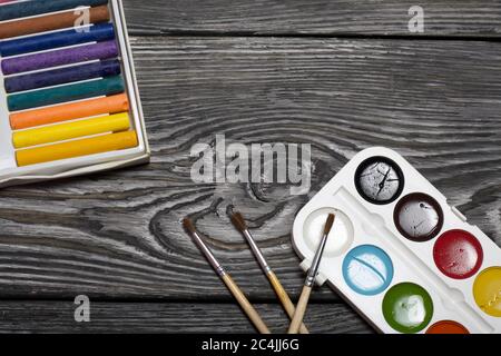 Acquerello per pittura e pennelli. Scatola con pastello. Si trovano su tavole di pino dipinte con vernice bianca e nera. Foto Stock