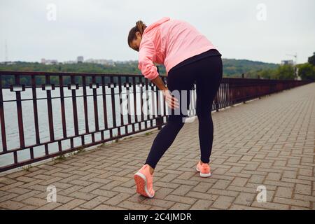 Sportiva che soffre di dolore alle gambe durante il suo allenamento all'aperto, spazio vuoto. Corridore con lesioni sportive all'esterno Foto Stock